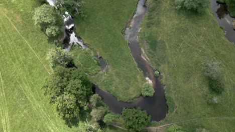An-aerial-view-of-the-tiny-river-Arrow-as-it-twists-it's-way-through-the-Warwickshire-countryside,-England