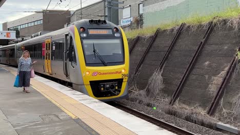 Brisbane-Translink-Eisenbahnzug,-Der-Am-Bahnhof-Bowen-Hills-Ankommt,-Mit-Passagieren-Und-Reisenden,-Die-Darauf-Warten,-Aus--Und-Einzusteigen-In-Den-Expresszug-Der-Beleigh-Linie