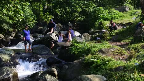 Tourists-relax-by-a-rocky-river-in-Sukabumi,-west-java,-Indonesia-on-May-4,-2022