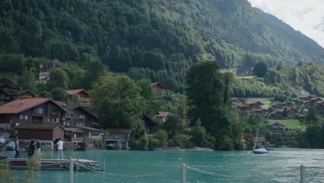 Iseltwald,-Switzerland,-walking,-ship,-pole,-pier,-tourists,-crowds,-scenic,-cloudy,-mountain,-lake,-hillside,-summer,-forests,-turquoise,-water,-europe