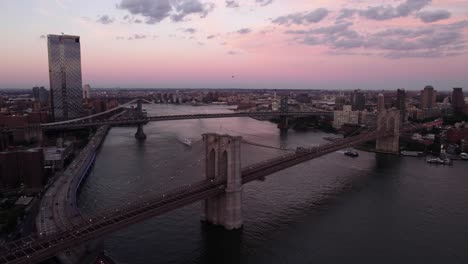 Aerial-view-around-the-Brooklyn-bridge,-colorful-dusk-sky-in-NYC,-USA---circling,-drone-shot