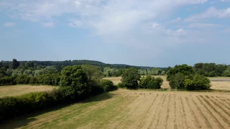 Fast-drone-shot-flying-over-a-farm-and-fields-in-English-countryside