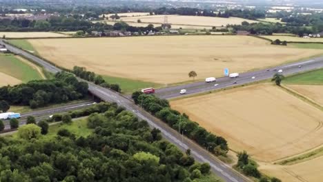 Aerial-view-across-agricultural-meadows-and-fields-in-rural-UK-countryside-following-M62-motorway