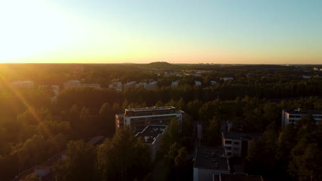 Forward-aerial-of-apartment-buildings-and-forest-in-Finland-at-sunset
