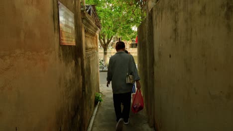 Una-Filmación-Estacionaria-De-Un-Campo-De-Visión-De-Un-Callejón,-Mirando-Hacia-Las-Calles-Con-Turistas-Y-Lugareños-Que-Caminan