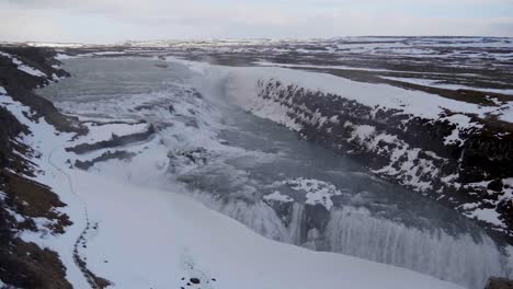 Static,-slow-motion,-wide-shot-of-gullfoss-waterfalls,-on-a-cloudy-and-snowy-autumn-day,-on-the-South-coast-of-Iceland