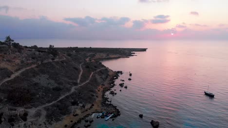 Aerial-drone-shot-over-Konnos-Bay-at-dusk-with-a-pink-purple-glow
