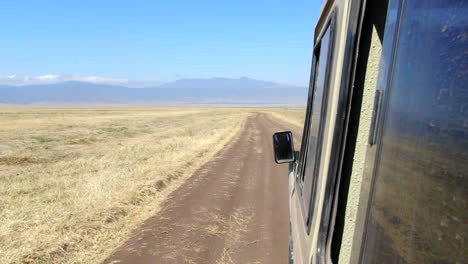 Vista-Desde-La-Ventana-De-Un-Vehículo-De-Safari-Conduciendo-Por-Un-Camino-De-Tierra-En-El-Serengeti