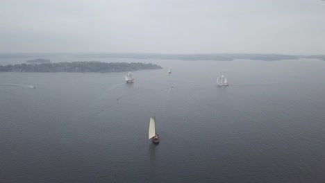 Aerial-footage-of-tradtional-wooden-sailing-ships-sailing-in-front-of-port-of-Helsinki-Finland