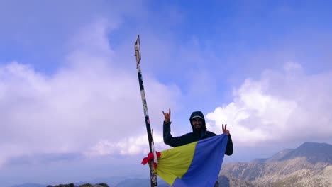 Hombre-Mirando-A-La-Cámara-Sosteniendo-La-Bandera-Rumana-Y-Agitando