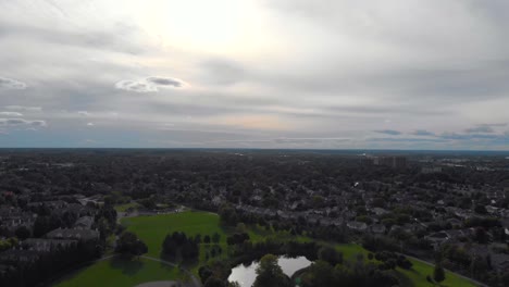 Aerial-footage-slowly-flying-down-over-a-park-and-the-swooping-In-between-a-green-tree-on-an-island-and-bushes-over-geese-in-the-water-on-a-warm-summer-cloudy-day