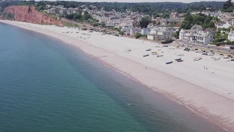 Aerial-STATIC-CROP-over-the-calm-ocean,-rising-to-reveal-the-town-of-Budleigh-Salterton,-UK