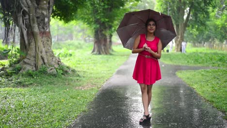 A-pretty-hot-Caucasian-girl-enjoys-the-rainy-season-on-road-with-her-umbrella,-Slow-motion