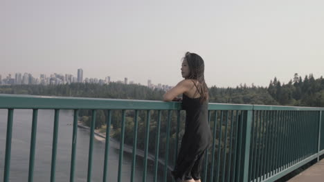 Wide-shot-of-asian-woman-enjoying-view-of-downtown-Vancouver-from-Lions-gate-bridge,-Slowmo