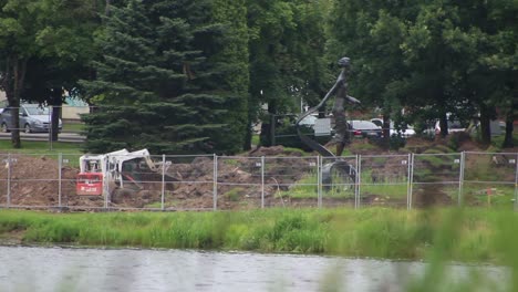 Minicargador-Minicargador-Bobcat-Arbeitet-Mit-Einem-Eimer-Am-Fluss