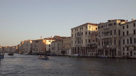 Small-boat-cruising-through-morning-Canal-Grande-in-Venice,-Italy
