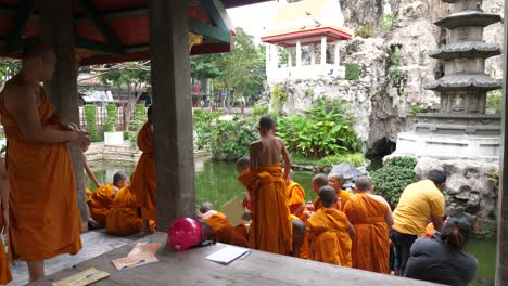 Monjes-Del-Templo-Wat-Prayoon-En-Bangkok-Desarrollando-Una-Actividad-Cerca-Del-Agua