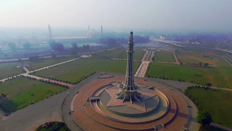 Aerial-rotating-view-of-Minar-e-Pakistan-with-city-and-Mughal`s-Famous-Badshahi-Mosque,-A-national-monument-located-in-Lahore,-Pakistan