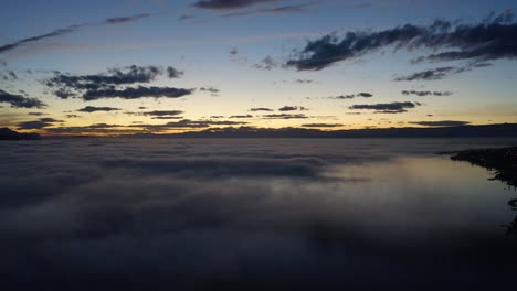 Aerial-shot-of-fog-patches-low-over-Lake-Léman-at-sunset-with-reflections-in-the-water