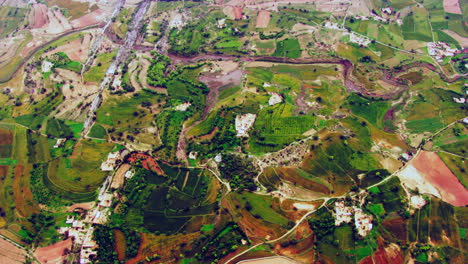 Aerial-view-of-farm-land-and-a-small-farming-community-with-River,-Agricultural-crops-growing-on-farmland,-India