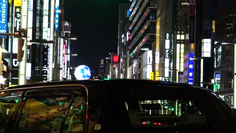 La-Vista-De-La-Famosa-Calle-Comercial-Ginza,-Autos-Y-Gente-Caminando-Por-La-Noche