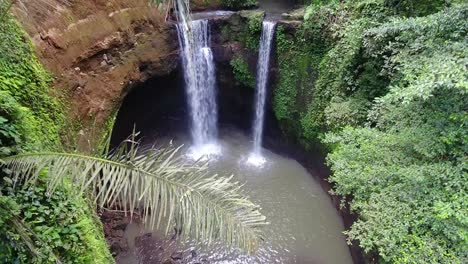 Beautiful-drone-shot-of-a-high-waterfall-with-small-pond-hidden-in-the-jungle