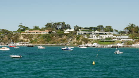 Multiple-mored-boats-along-a-seaside-coastal-town-on-a-stunning-blue-sky-day