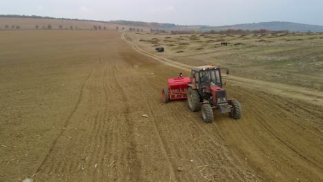 Tractor,-agricultural-machinery-and-workers-sow-a-field---aerial-tracking-shot