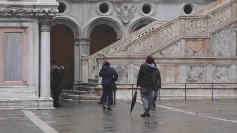 Gruppe-Von-Touristen,-Die-Nach-Regenfällen-In-Venedig-Im-Hof-Des-Dogenpalastes-Spazieren-Gehen