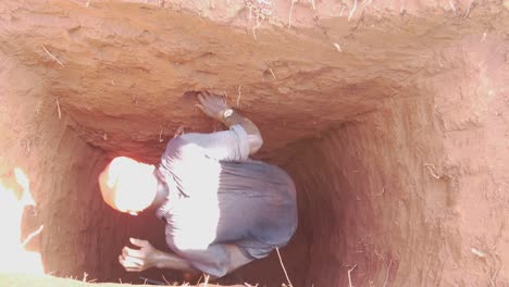 Vista-De-Pájaro-Mirando-Hacia-Abajo-En-Una-Letrina-Excavada-En-África-Con-Un-Joven-Trabajador-Saliendo-Del-Agujero-Profundo