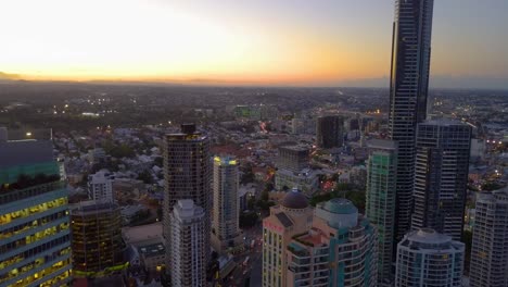 Backward-moving-aerial-view-of-tall-buildings-at-sunset