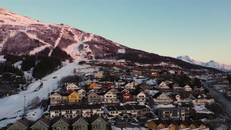Aerial-view-of-mountain-in-sunset-with-ski-slope-close-to-a-city