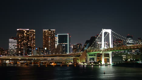 Tokio,-Japan---Ca.-Farbenfroher-Nächtlicher-Zeitraffer-Von-Wahrzeichen-Der-Regenbogenbrücke,-Verkehrsgebäuden-Und-Booten