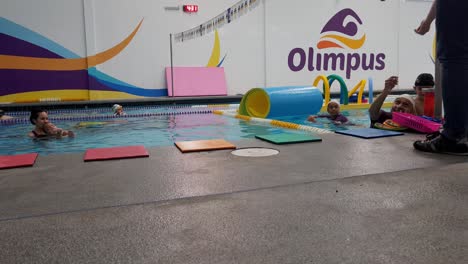 Niños-Aprendiendo-A-Nadar-Con-Instructores-Enseñándoles-Y-Cuidándolos-En-La-Escuela-De-Natación-&quot;olimpia&quot;