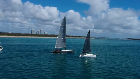 Three-sailing-boats-travelling-along-a-waterway-close-to-a-capital-city