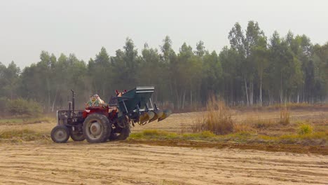 A-farmer-operates-his-tractor-in-the-field-near-a-Eucalyptus-forest