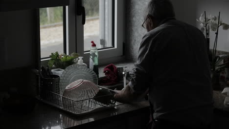 Pensioner-washing-up-by-the-window,-silhouette