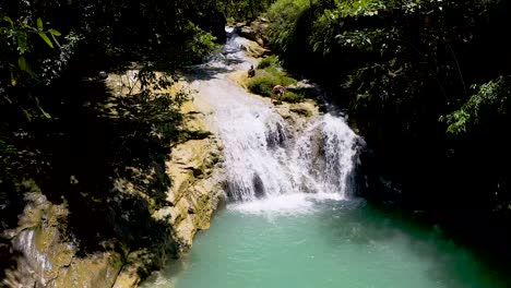 Man-climbs-down-a-slippery-rock-at-the-top-of-a-waterfall-in-the-jungles-of-Bohol,-Philippines