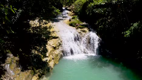 El-Hombre-Baja-Por-Una-Roca-Resbaladiza-En-La-Cima-De-Una-Cascada-En-Las-Selvas-De-Bohol,-Filipinas