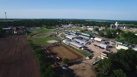 Aerial-pull-back-from-water-truck-wetting-down-the-dirt-arena-at-the-equestrian-center,-​Kansas,-Missouri