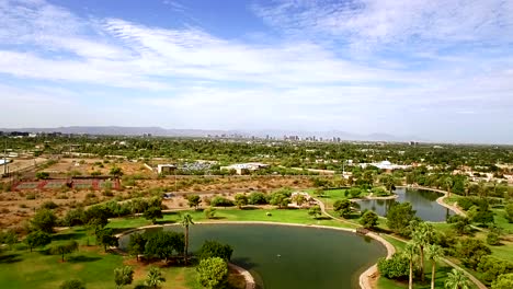 Aerial-pull-back-from-Phoenix-skyline-to-the-water-features-at-Granada-Park,-​North-Phoenix,-Arizona