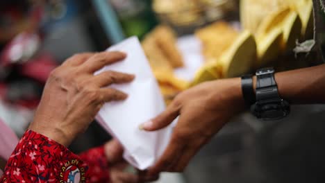 Aufnahme-Eines-Straßenverkäufers,-Der-Auf-Einem-Markt-In-Den-Straßen-Von-Jakarta-Einem-Hungrigen-Kunden-Sein-Frittiertes-Indonesisches-Essen-Verkauft
