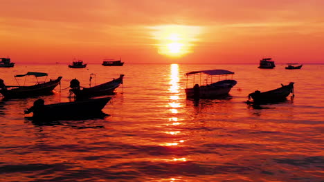 Toma-Aérea-De-La-Isla-De-Koh-Tao,-Super-Puesta-De-Sol-En-La-Playa-De-Sairee-Con-Muchos-Barcos-Flotando-En-Tailandia