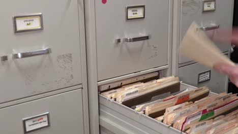 Young-Adult-Male-Office-Worker-Looking-Through-a-Folder-in-a-File-Cabinet-Room