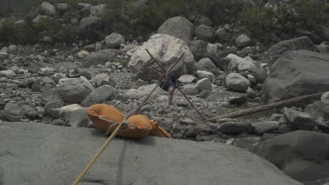 A-trainer-of-a-mountaineering-institute-of-the-Himalayas-crossing-the-mountainous-river-by-rope,-practicing-to-cross-the-river-with-rope