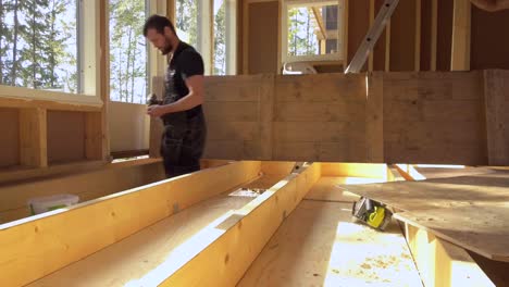 Motion-time-lapse-of-Carpenters-preparing-floor-with-plywood-sheets-before-installing-isolation,-in-small-country-cabin