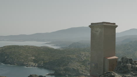 Panoramic-view-of-a-tower-near-Cap-de-Creus-where-a-lot-of-seaguls-are-circling-around-and-people-walking-by