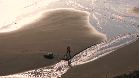 Man-walks-across-the-beach-on-black-sand-beach-in-Iceland