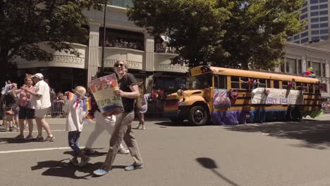 Seattle-Public-School-employees-and-students-participating-in-the-Seattle-LGBTQ-parade,-School-bus,-waving-rainbow-flags