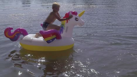 Summer-boy-riding-an-inflatable-unicorn-in-water